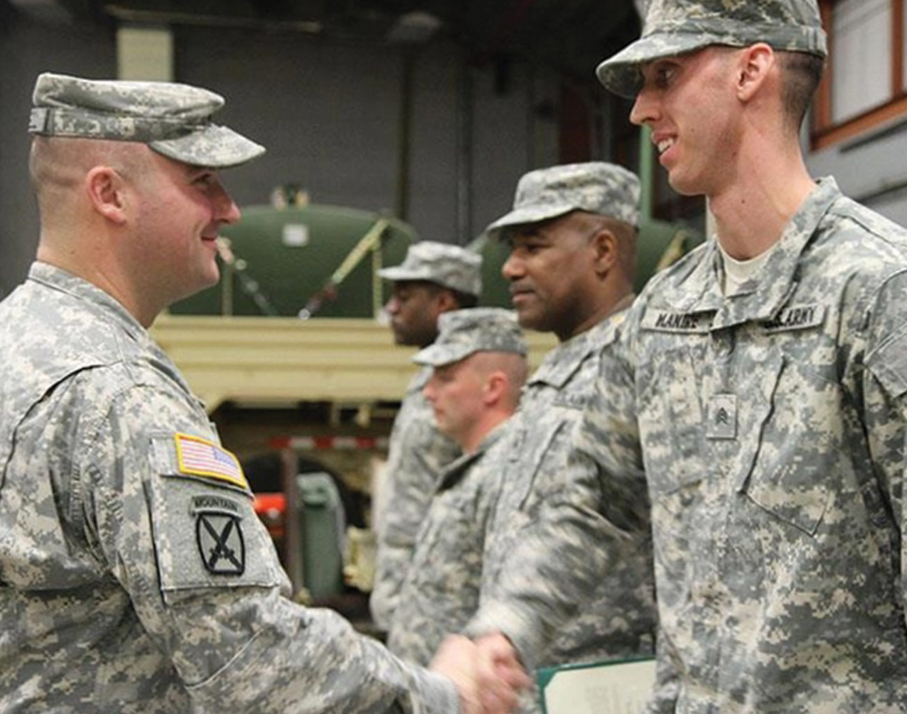 a unit commander shakes hands with a newly promoted sergeant