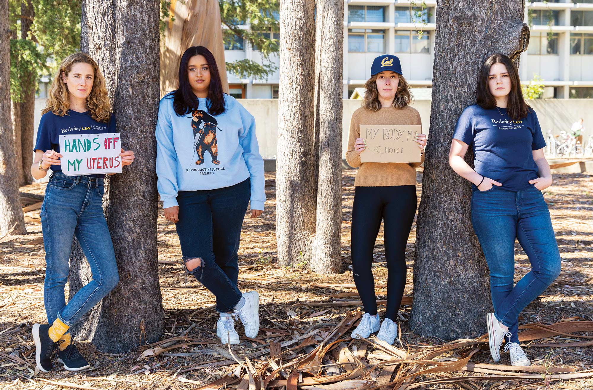 Florence Van Dyke, Jade Williams, Jacqueline Berkenstadt, and Camille Tabari standing with signs by trees