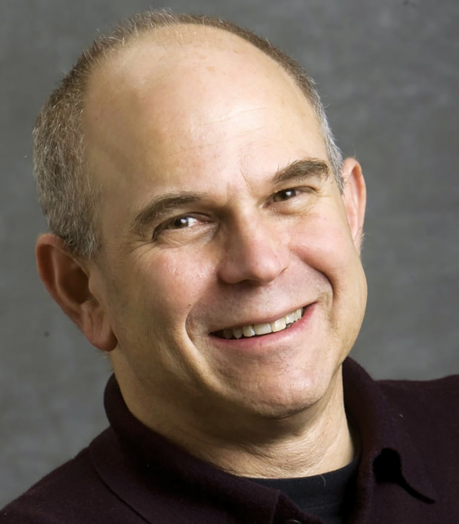 A portrait headshot photograph of David Lieberman smiling in a dark burgundy button-up polo t-shirt