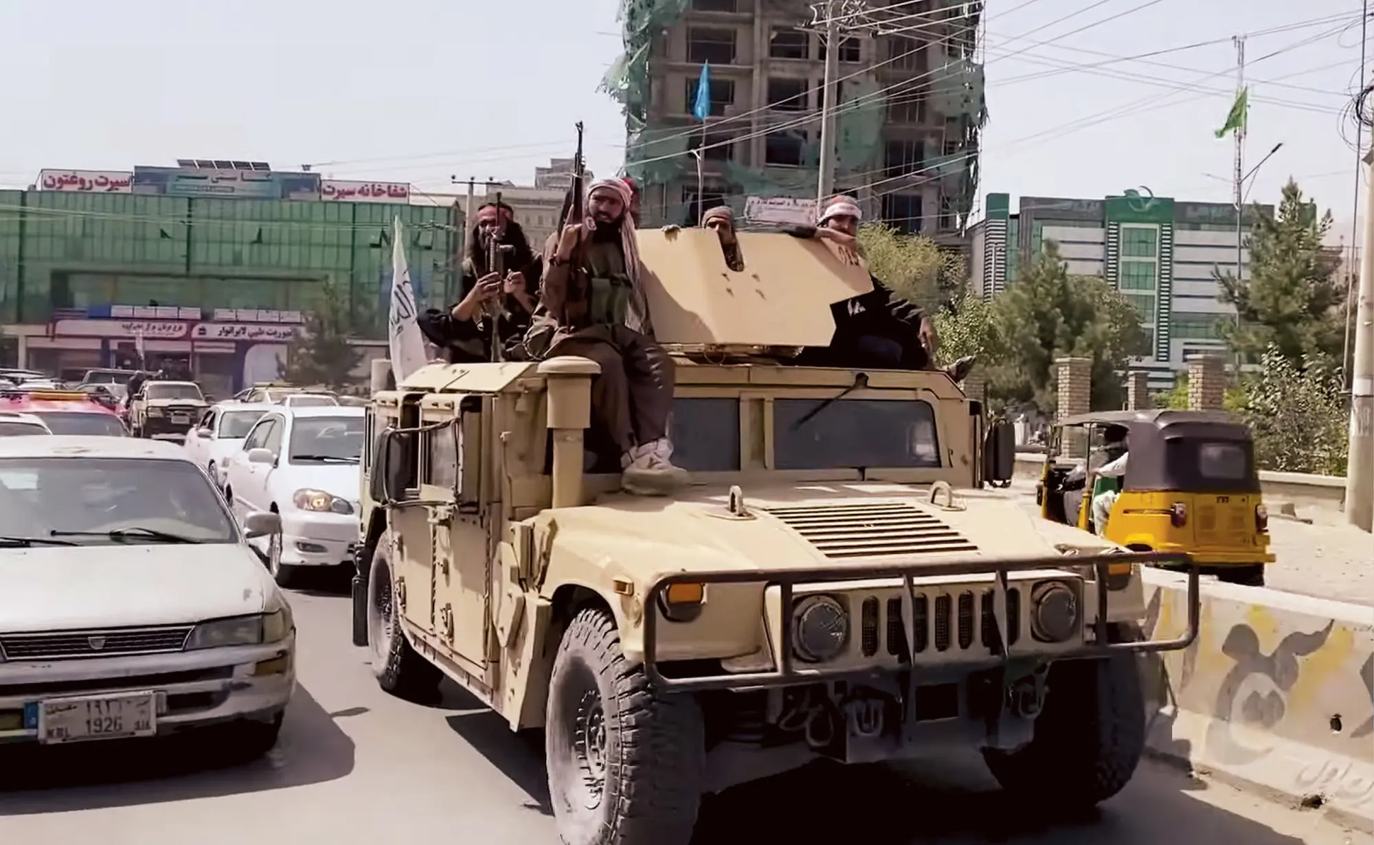 Armed Taliban militia patrolling city in military vehicle