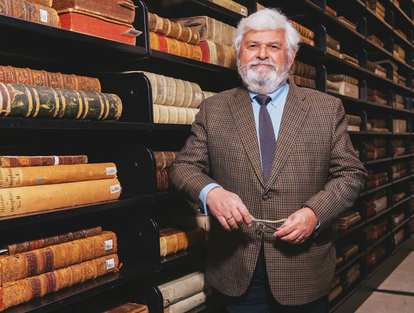 Laurent Mayali smiles in a green plaid suit inside a fancy library
