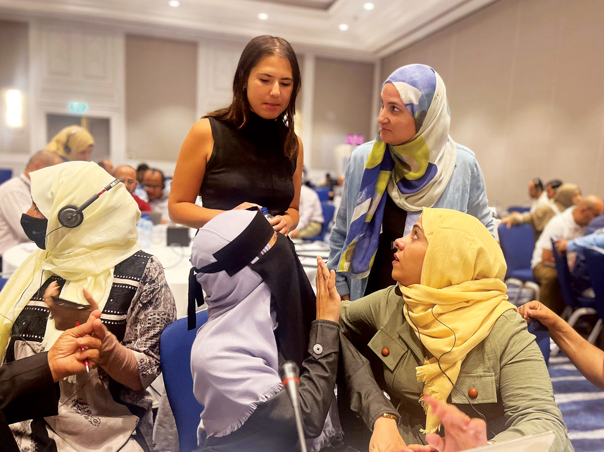 three female Yemen delegation members discussing with the Human Rights Center’s Ceren Fitoz in a large meeting group
