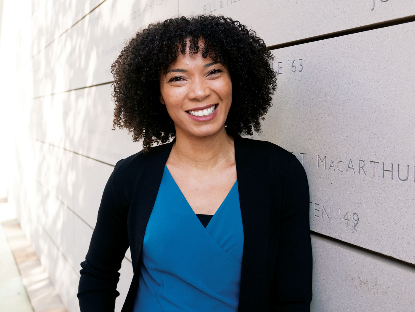 Alina Ball smiling and leaning against wall outside