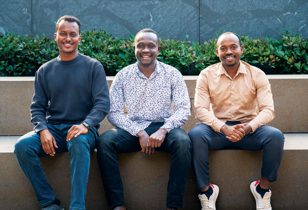 Three individuals sitting on a concrete bench, smiling.