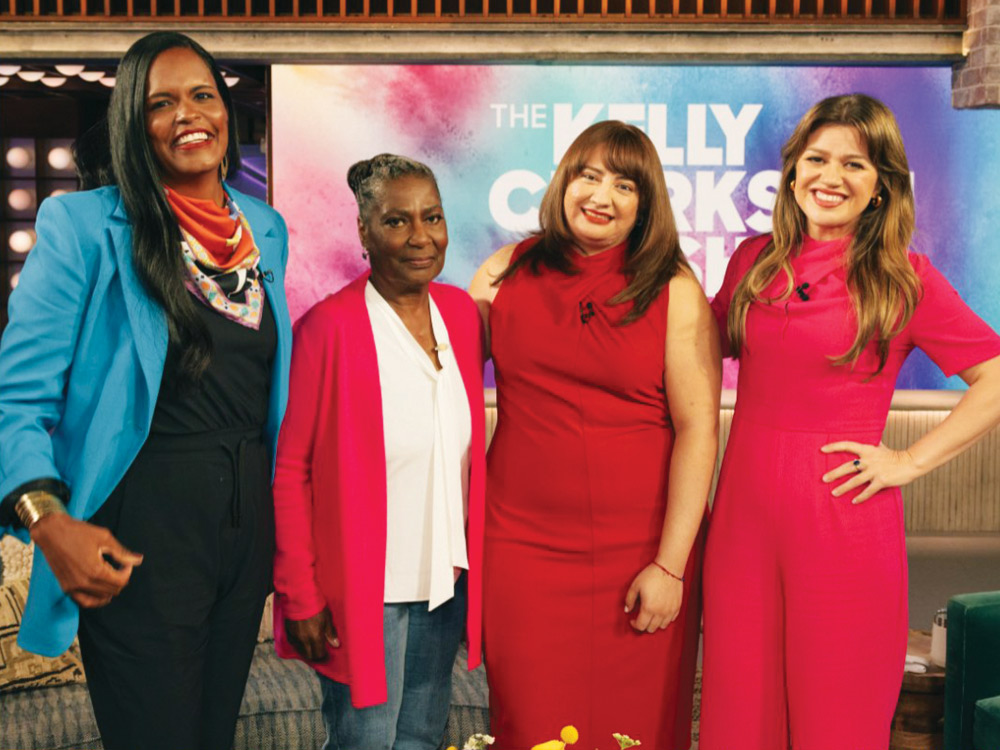 Four women on the set of "The Kelly Clarkson Show" wearing colorful outfits.