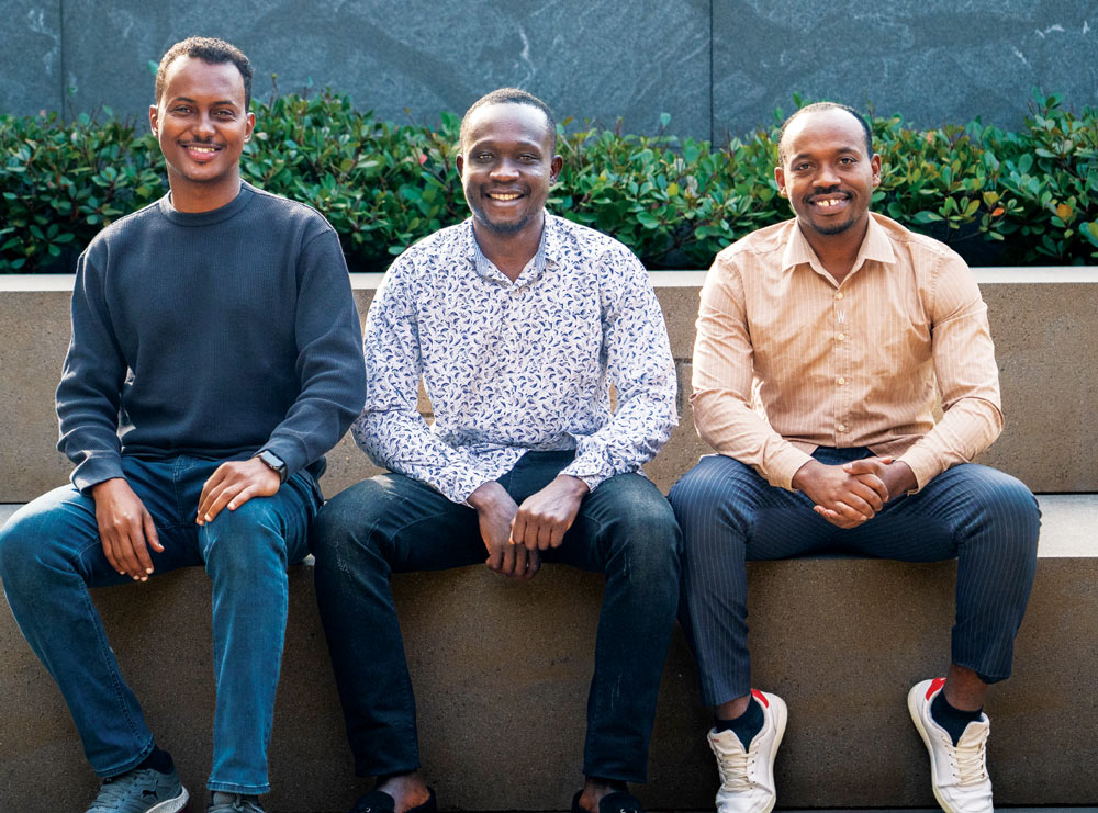Three individuals sitting on a concrete bench, smiling.