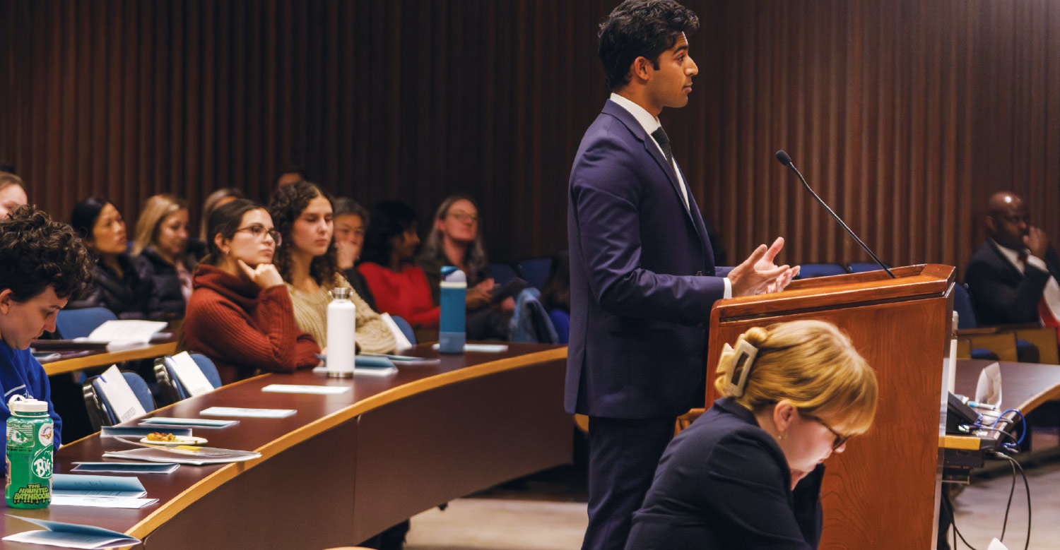 Hersh Gupta speaking at podium during finals